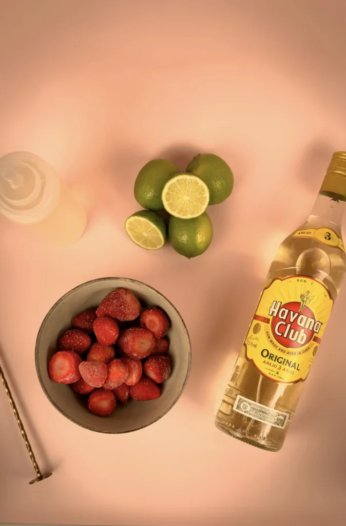 Ingredienser till strawberry daiquiri - ljus rom, frysta jordgubbar, färsk lime och sockerlag