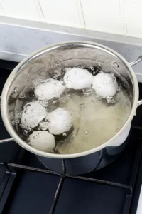 Perfekta ramenägg - instruktioner steg ett. ANvänd en stor kastrull för att äggen inte ska krocka för mycket. TIllsätt salt och vinäger för att undvika läckor