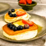 Recept på fluffiga japanska pannkakor serverade med färska bär (blåbär och jordgubbar), smör och lönnsirap - sufflepannkakor!