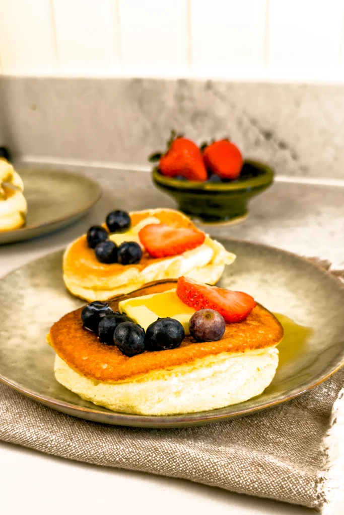 Recept på fluffiga japanska pannkakor serverade med färska bär (blåbär och jordgubbar), smör och lönnsirap - sufflepannkakor!